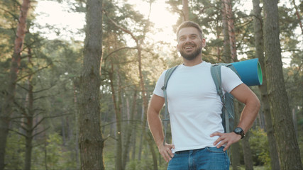 Happy man with beard and backpack in forest uses phone to touch the screen smiling gps application orientation tourist travel hike lost sun communication telephone slow motion