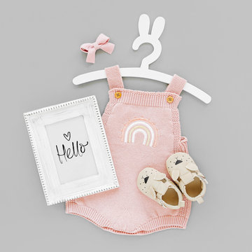 Pink knitted bodysuit on cute hanger with bunny ears with photo frame and baby boots. Set of kids clothes and accessories summer. Fashion newborn. Flat lay, top view