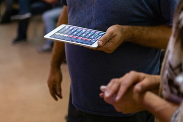 Closeup midsection of male showing digital tablet screen and discussing stock market to his female friend in auditorium hall