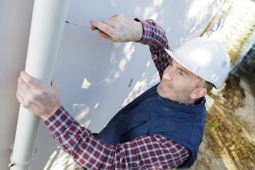 workman replacing guttering on exterior of house