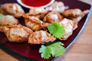Crispy deep-fried wontons on wooden plate serve with sweet chilli sauce.