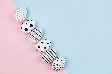 Many easter eggs on trendy pink pastel background. Eggs are hand-drawn. Flat lay style.