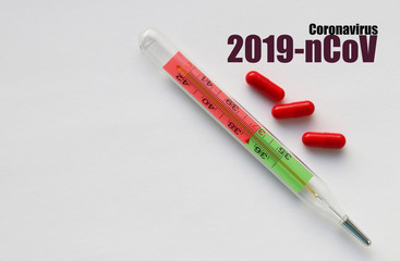 Three capsules and a thermometer on a light background and words in dark font: 2019-nCoV...