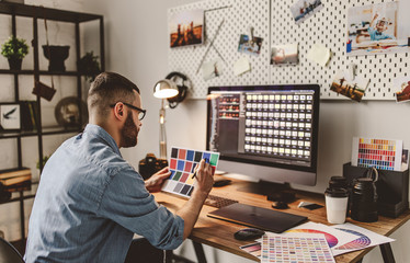 young man is a freelance photographer working on  computer