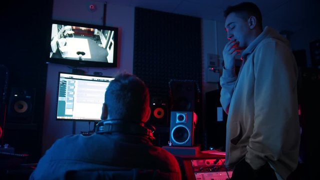 A man sound engineer working on the rap track with the artist