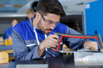 young worker cutting metal frame