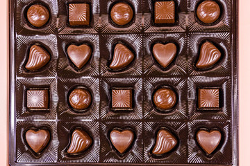 Heap of chocolate candies in a brown box. Top view