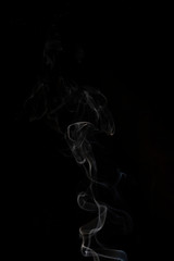 Delicate column of smoke from incense stick isolated on black background, selective focus