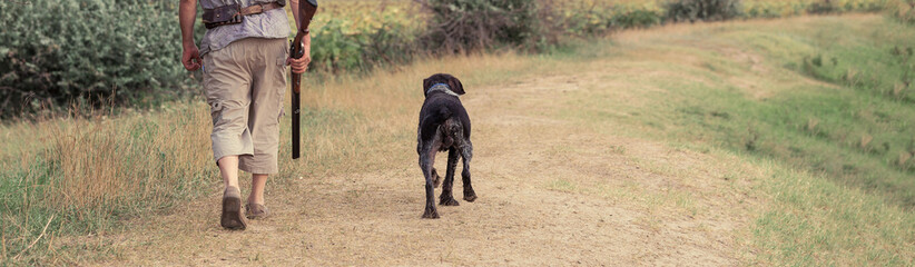 A man with a gun in his hands and an green vest on a pheasant hunt in a wooded area in cloudy...