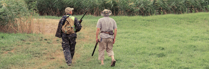 A man with a gun in his hands and an green vest on a pheasant hunt in a wooded area in cloudy...
