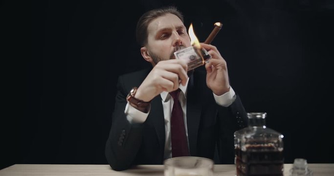 Rich bearded man smoking cigar and burning dollar banknote, vanity