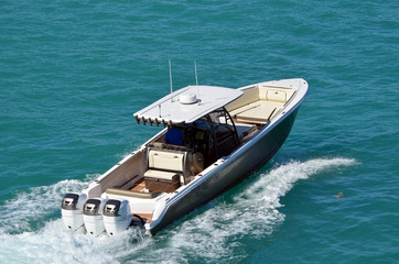Upscale sport fishing boat powered by three outboard engines speeding across Biscayne Bay off Miami...