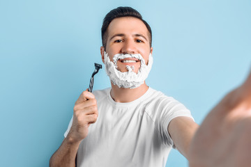 Positive young man with a beard shaves