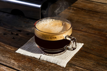 A cup of coffee on a wooden table in the morning light