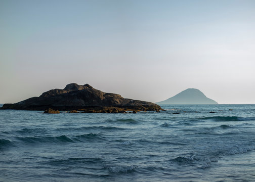 Seascape with a rock and an island at the background