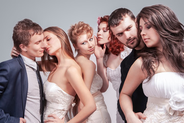 Obraz premium Closeup of Group of Five Loving Caucasian People Standing in Pairs of Two in Wedding Clothing. Against Gray Background.