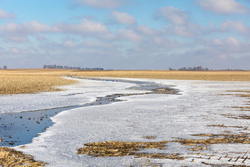 Flooded farm field after winter rain storms with water turning to ice as temperature dropped below freezing
