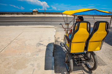 Bicitaxi amarillo en el malecón de la Habana , Cuba. Medio de transporte utilizado para llevar...