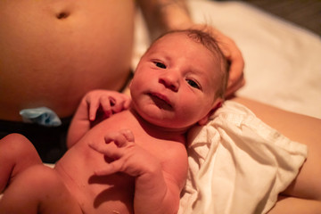 A close up shot of a cute baby boy opening eyes for first time in postpartum room, moments after...