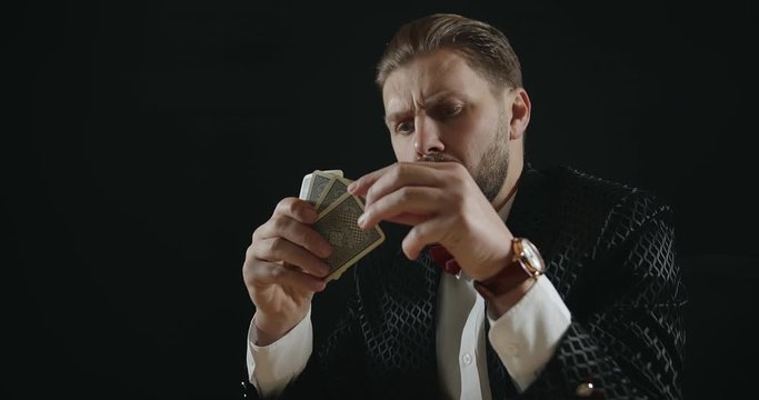 Thoughtful masculine male playing cards in poker club, making decision, gambling addiction