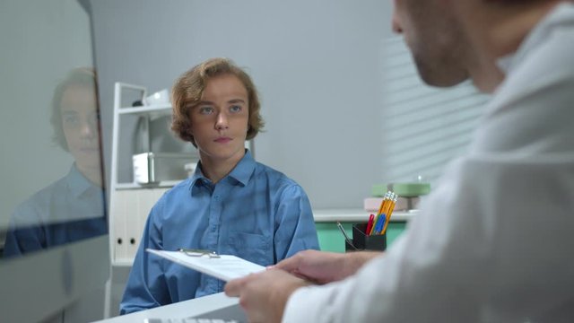 Doctor talk to boy in cabinet of hospital