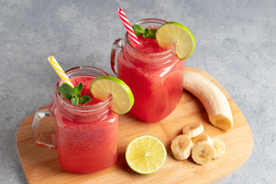 Watermelon smoothie with banana, lime and mint in mug jars on a cutting board. Healthy eating concept