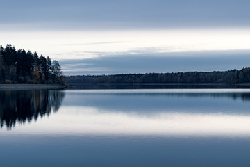 Serene landscape. Sunset on the lake, calm water surface, symmetrical reflection