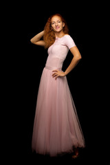 Red-haired young woman in the studio on a black background.