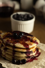 A stack of gluten-free pancakes with black currant on a dark background and topping