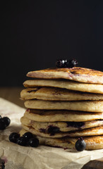 Oatmeal pancakes with black currant close-up on a black background