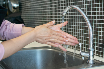 Cropped shot view of woman  washing hands at sink basin faucet in kitchen room. Washing your hands is one of the easiest ways to protect yourself and others from illnesses.