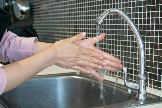 Cropped shot view of woman  washing hands at sink basin faucet in kitchen room. Washing your hands is one of the easiest ways to protect yourself and others from illnesses.