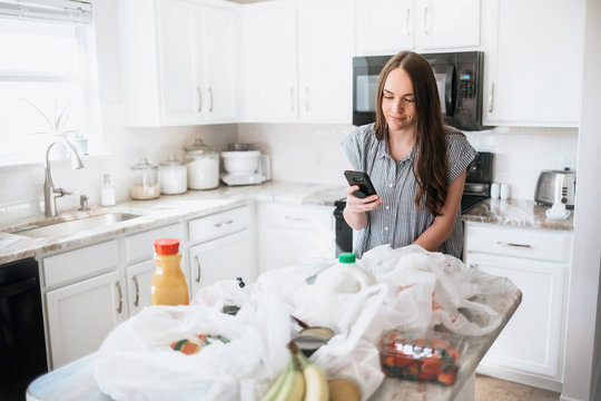 Lifestyle Of Women Unloading Her Groceries At Home In A White Kitchen