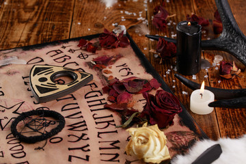 Talking board and planchette, also known as Ouija board, used for communicating with the dead and other spirits. The atmosphere of black art with candles and horns of the animal.
