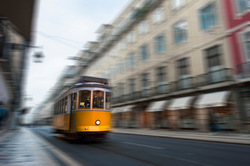 Yellow electric tram drive fast on old streets and colorful buildings of Lisbon, Portugal, digital...