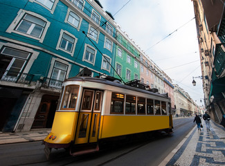 Yellow electric tram on old streets and colorful buildings of Lisbon, Portugal, popular tourist attraction commercial square