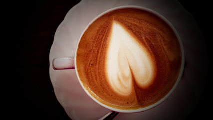 Cappuccino coffee heart shape in white cup.