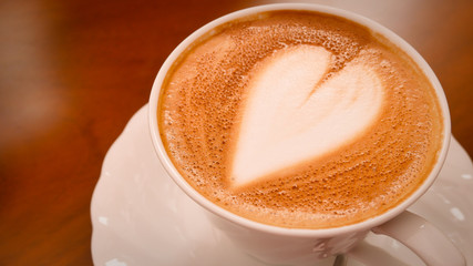 Cappuccino coffee heart shape in white cup.
