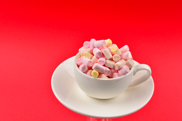 Cup with marshmallow on a red background. Copy space.