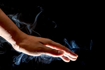 A close up of hand showing and smoky black background