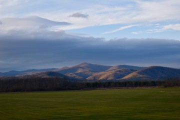 Cloudy skies and mountains with green fields