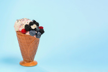 Ice cream with blueberries, blackberries and raspberries on a blue background.  Copy space.