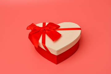 Box. Gift box with a red ribbon heart-shaped stands on the middle on a pink background. Valentine's day and Birthday