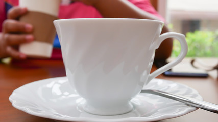 White cup and spoon on wood table.