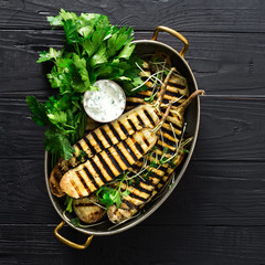 Grilled eggplant in a pan on dark wooden background with copy space