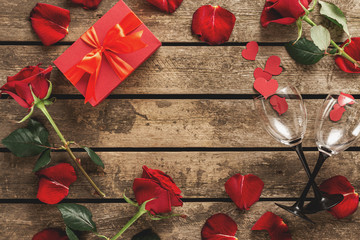 Valentines day  mothers day Frame red gift box with flowers rose petals wine glasses on wooden background top view