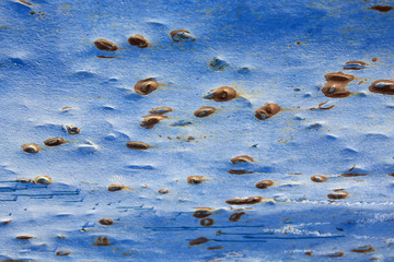 Abstract background of peeling white paint on a blue wall, rust on a cold wall