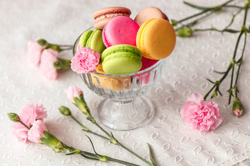 Sweet pink raspberry macaroons on white wooden table with roses on a background. Sweetness concept