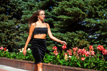 Sexy beautiful young brunette woman in skirt and black bra, posing on summer street
