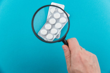 Pharmaceutical research and clinical trials concept. New medical drug in pills under magnifying...
